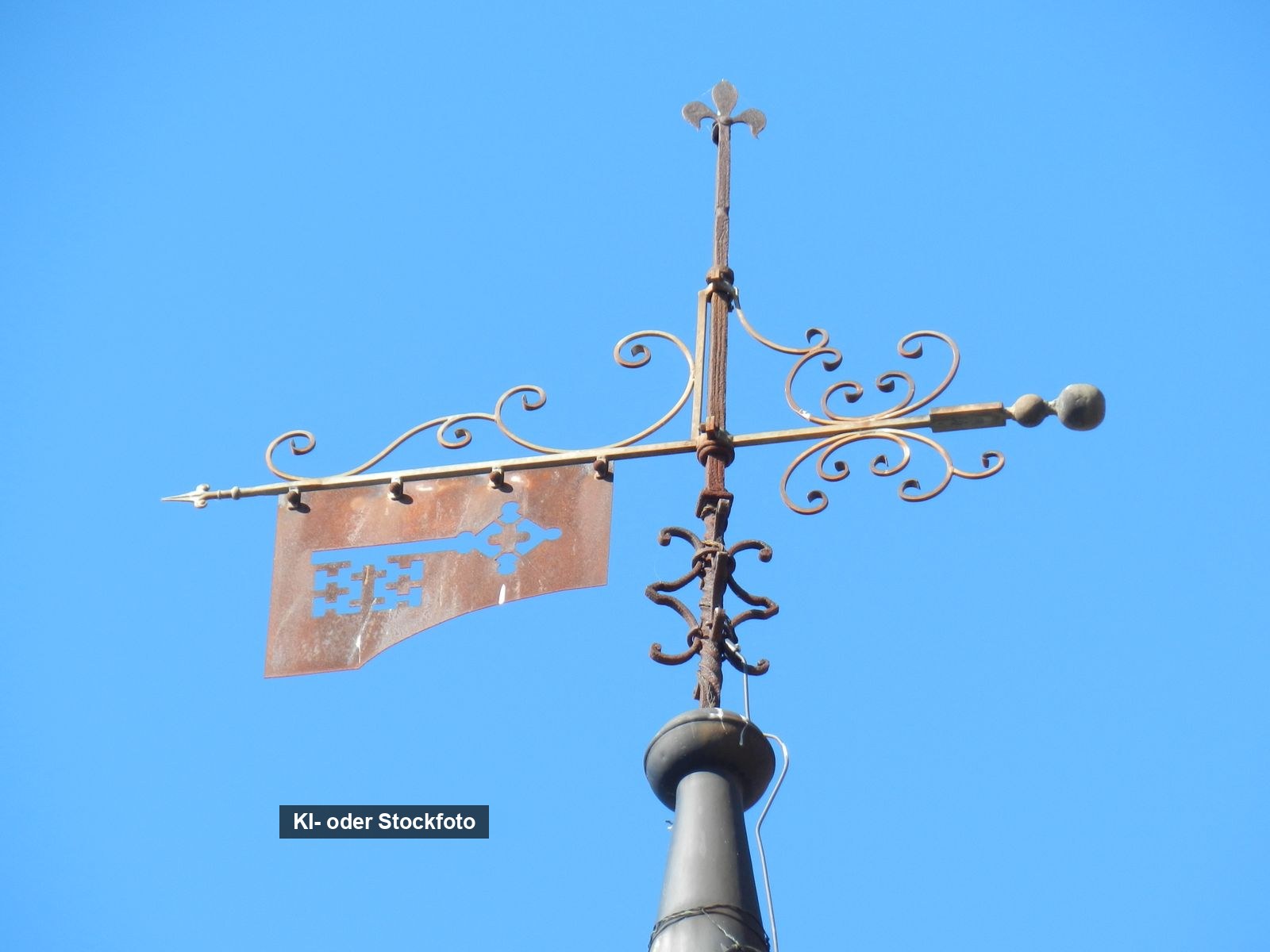 Schmiedeeiserne Wetterfahne mit Schlüsselmotiv vor blauem Himmel