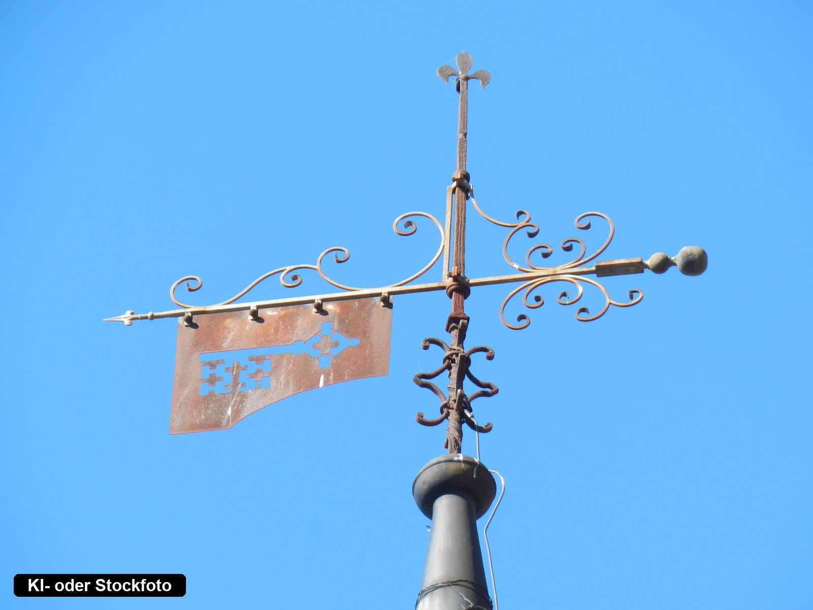 Schmiedeeiserne Wetterfahne mit Schlüsselmotiv vor blauem Himmel