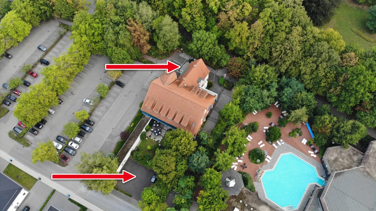Luftbild des Flair Hotels zur Therme mit dem hoteleigenen Parkplatz auf der Südseite; zwei rote Pfeile markieren die Zufahrten